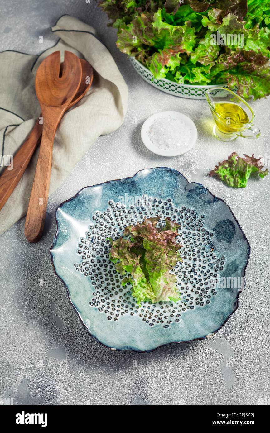 Modern ceramic bowl with wooden salad cutlery and bowl of lettuce on