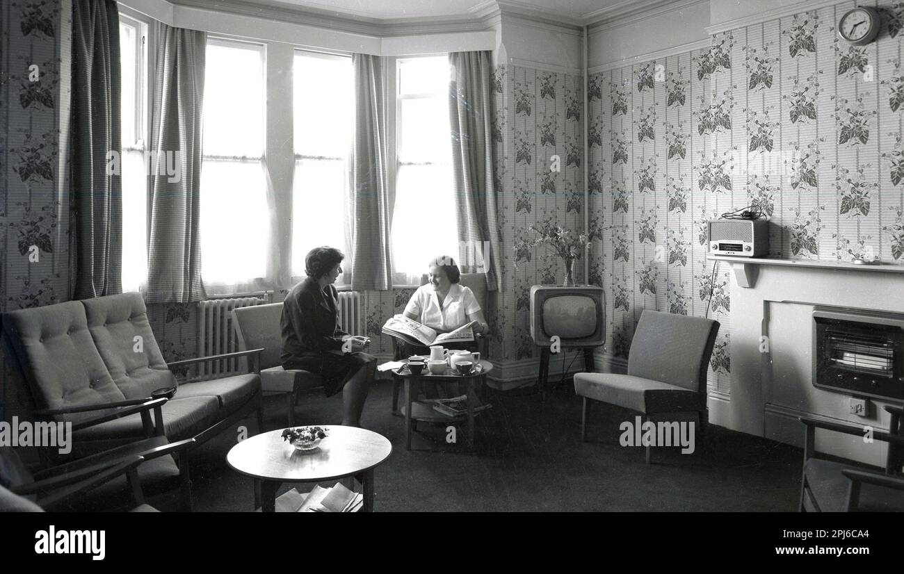 1950s, historical, lady house manager sitting with a female member of the kitchen staff inside a lounge room at the hostel at Littlemore, a mental health facility at the Littlemore Hospital, Oxfordshire, England, UK. Stock Photo