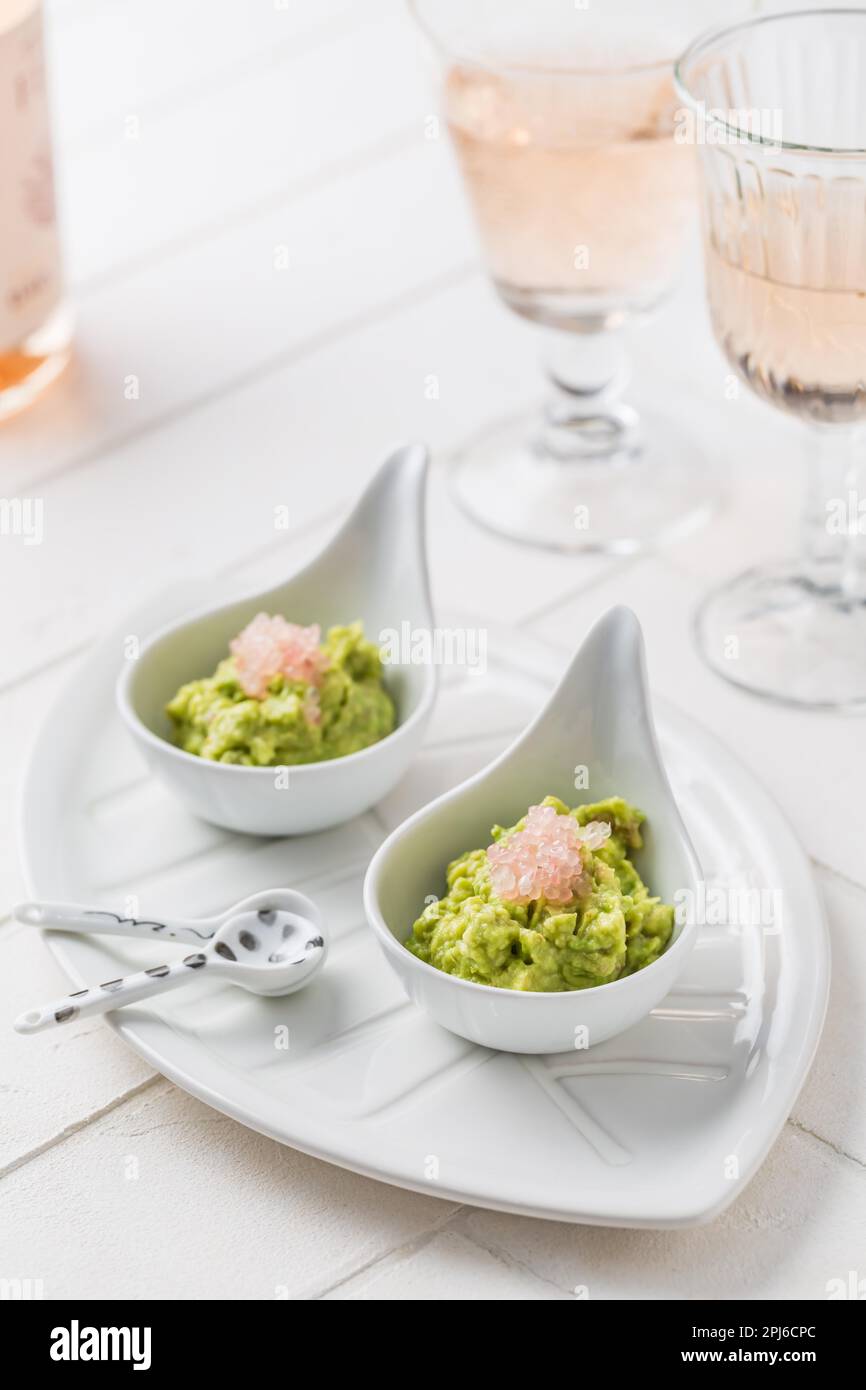 Fresh guacamole with caviar lime (Australian finger lime) fruits and rose sparkling wine on white background Stock Photo