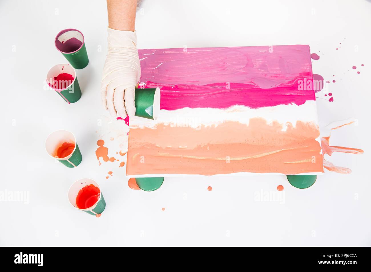 Acrylic pouring technique acrylic pour action photo of paint spreading on canvas with cup