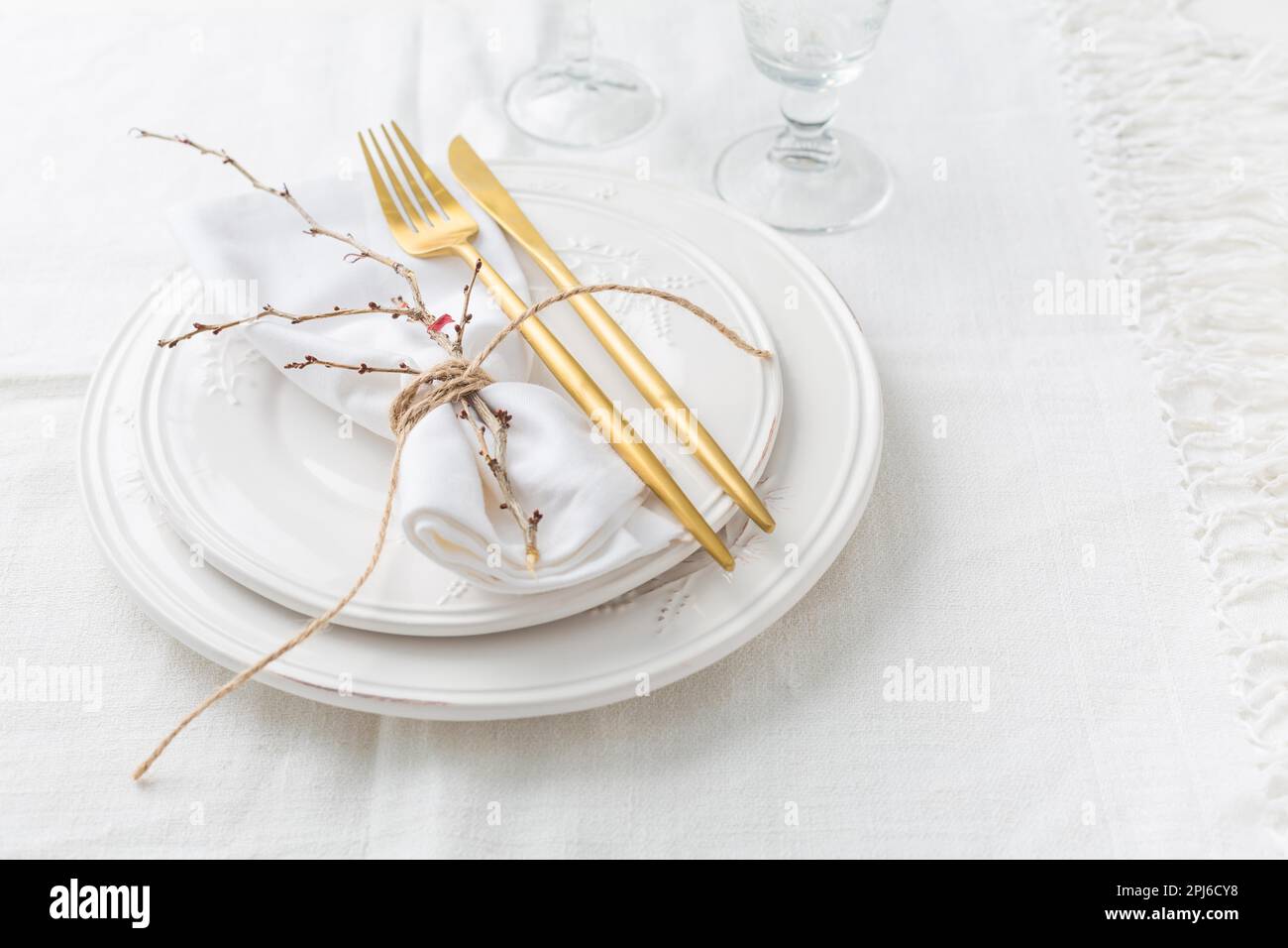 Place setting in white - plates, cutlery in gold, napkin Stock Photo
