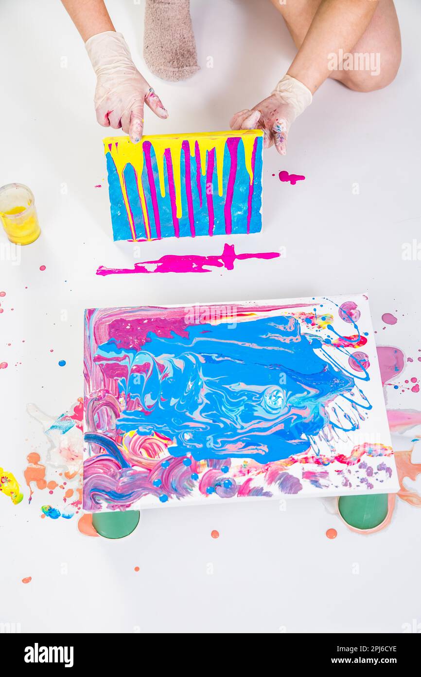 Acrylic pouring technique acrylic pour action photo of paint spreading on canvas with cup