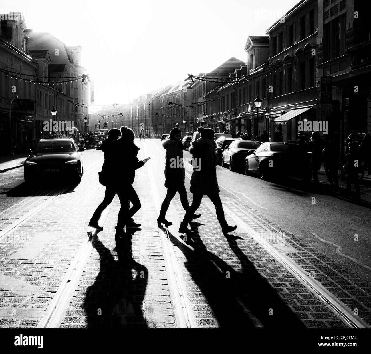 Black and white photograph, passers-by on the roadway in the backlight 