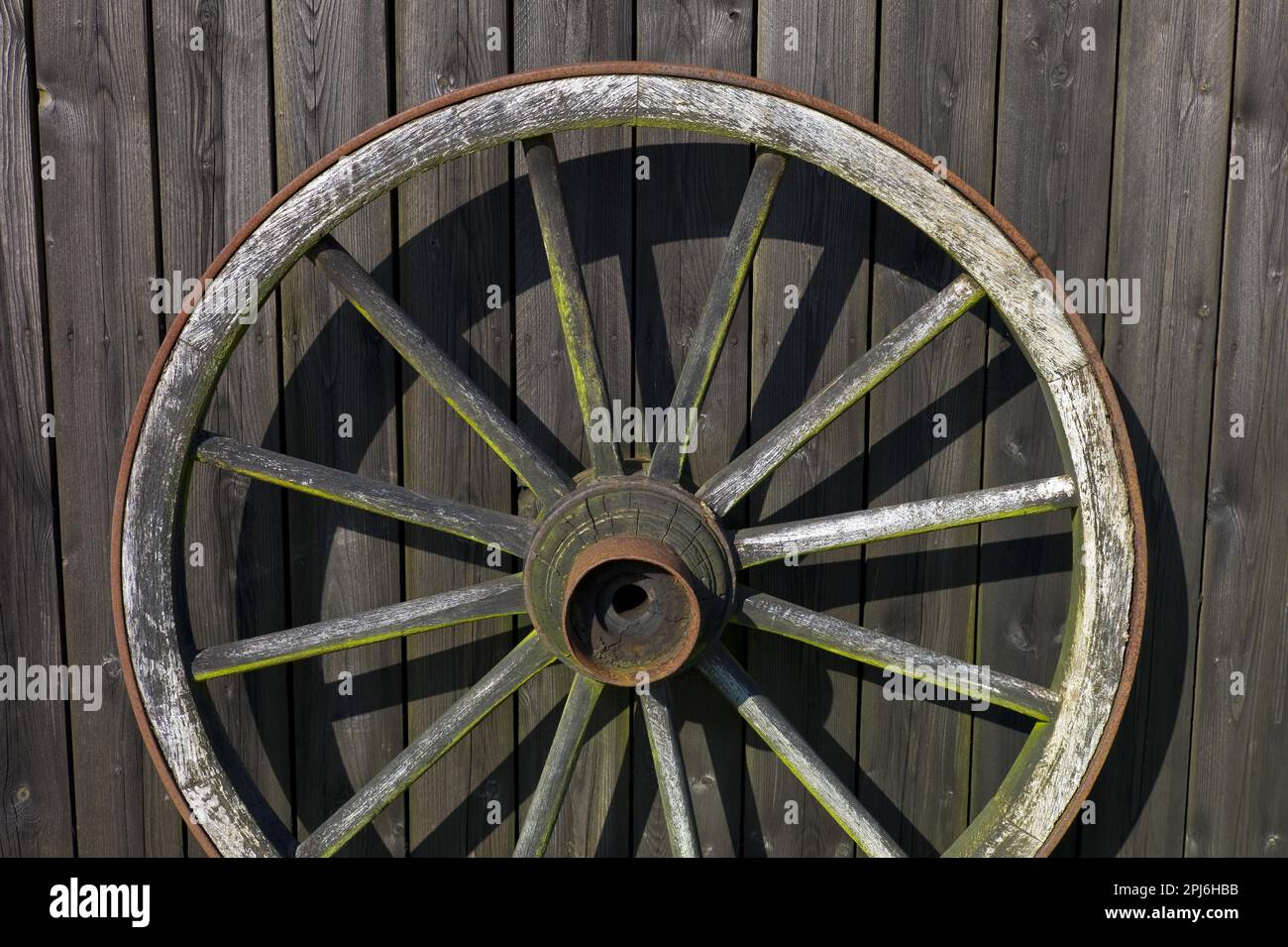 Wooden wagon wheel leaning against a shed wall Stock Photo Alamy