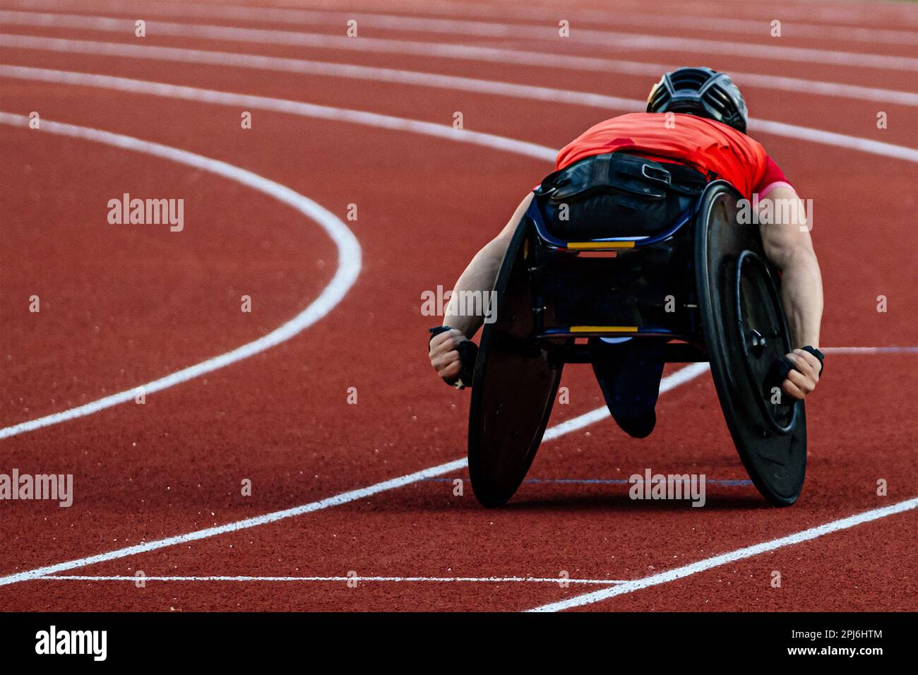 male athlete in wheelchair racing red track stadium in para athletics competition, summer sports games Stock Photo