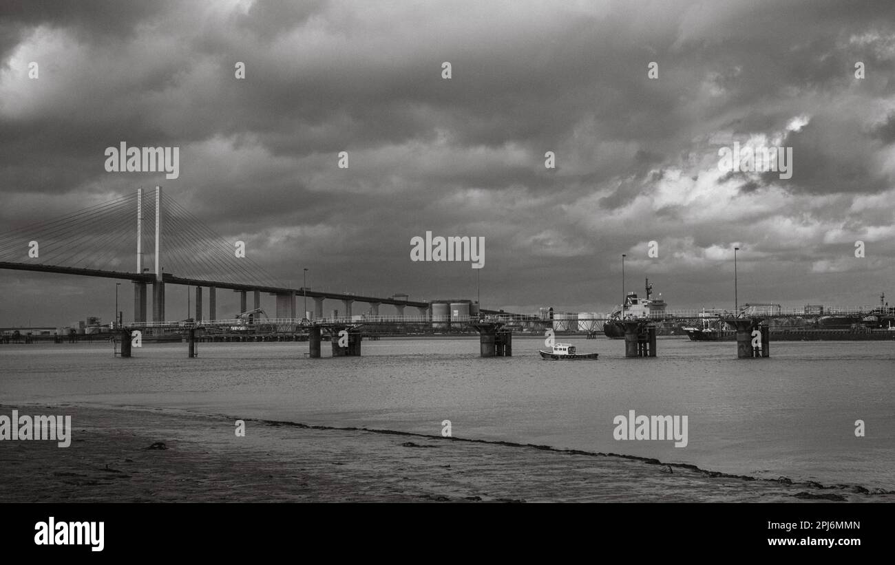 A small boat and other shipping on the River Thames next to the Dartford Crossing, or QE2 Bridge near London, UK. Stock Photo