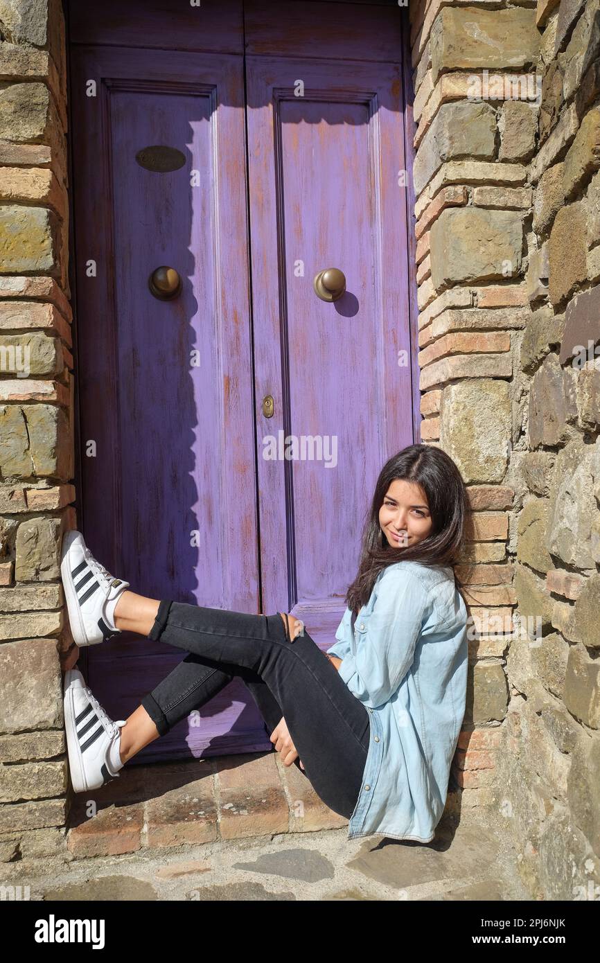 Young teenage girl sitting on stairs of typical tuscan house entrance in Montalcino,Tuscany, Italy Stock Photo
