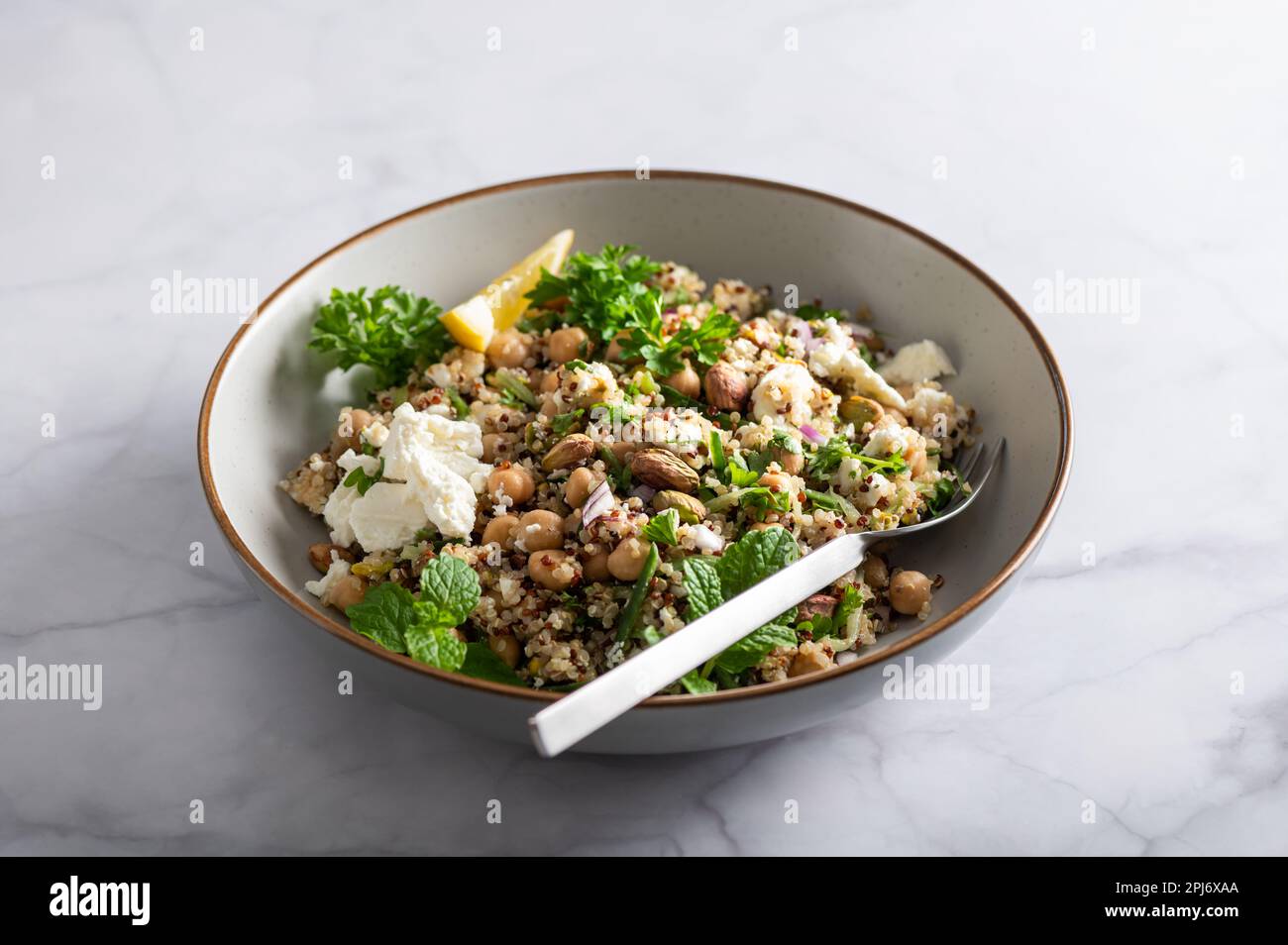 Healthy Salad made from Quinoa, Cucumber, Herbs, Pistachios, Chickpeas and Feta with lemon juice