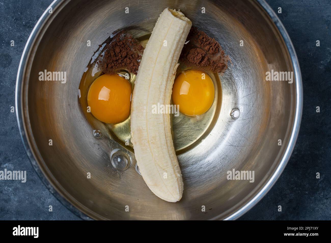 Metal bowl with eggs, ripe banana and cocoa powder for making banana  pancakes. Funny food in the shape of a face, close-up Stock Photo - Alamy
