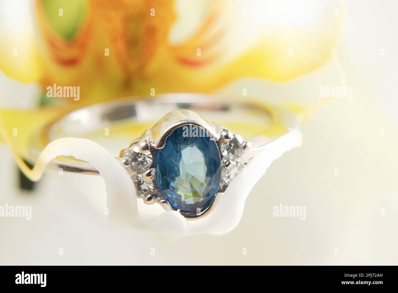white gold ring with diamonds lies on a blooming orchid macro photo Stock Photo