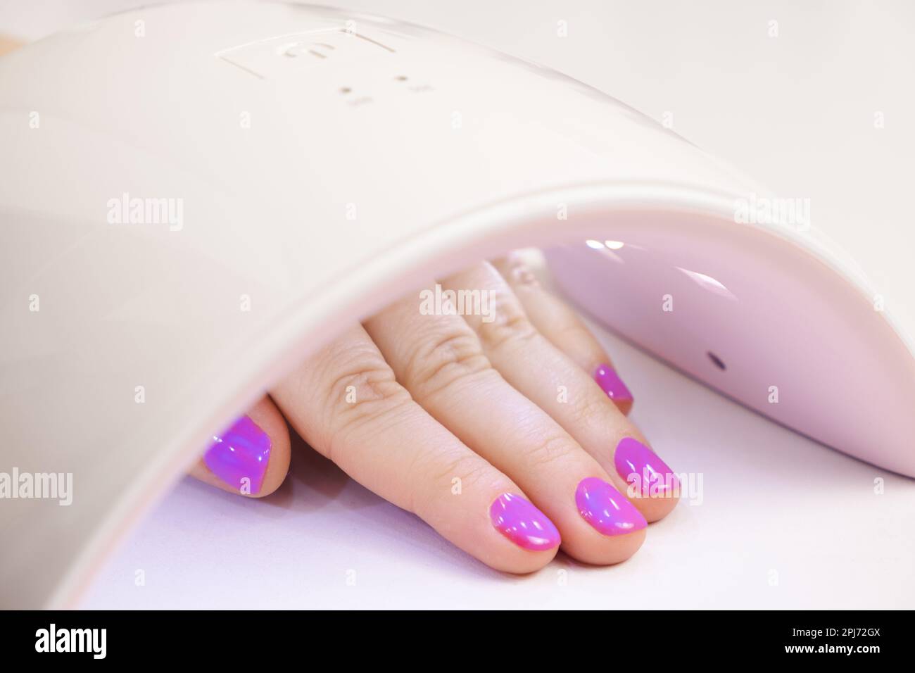 Drying the top for gel polish in an ultraviolet LED lamp. Manicure