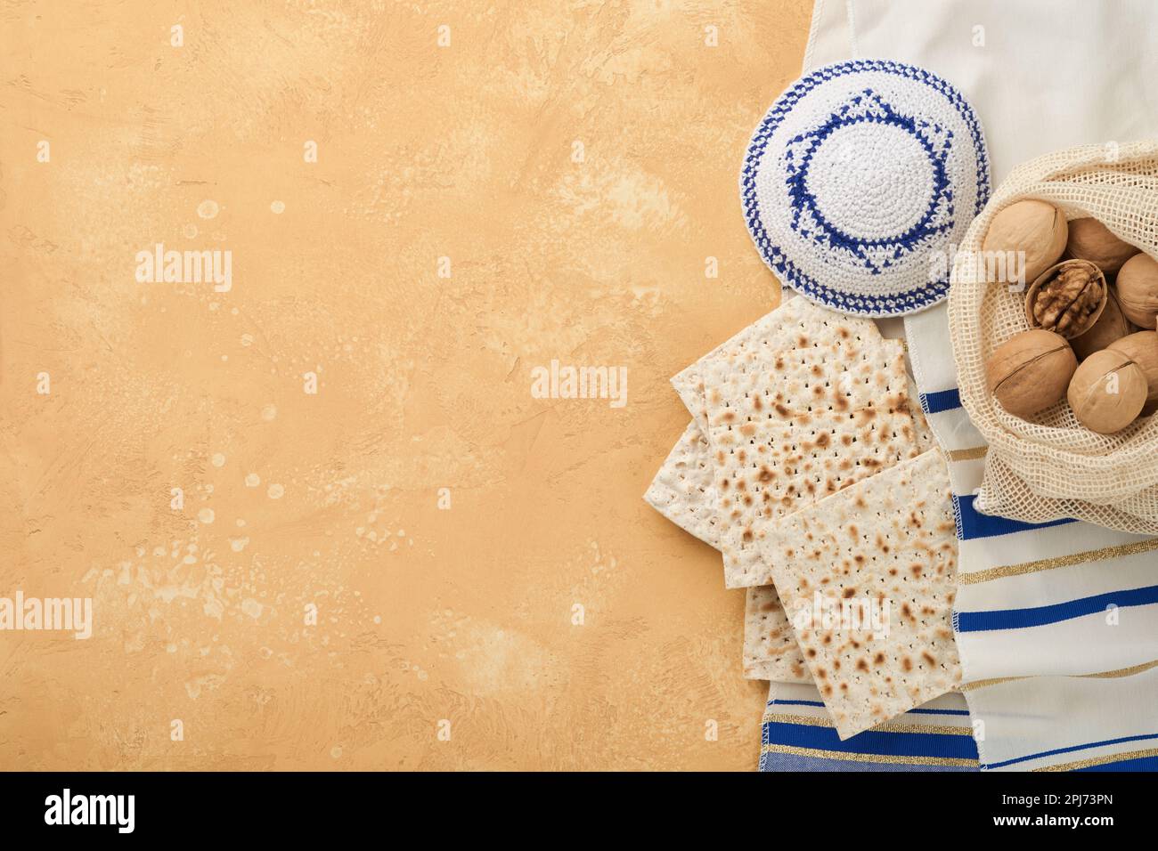 Passover Pesah celebration concept. Matzah, kosher red wine, walnut and white and yellow roses. Traditional ritual Jewish bread on sand color old tile Stock Photo