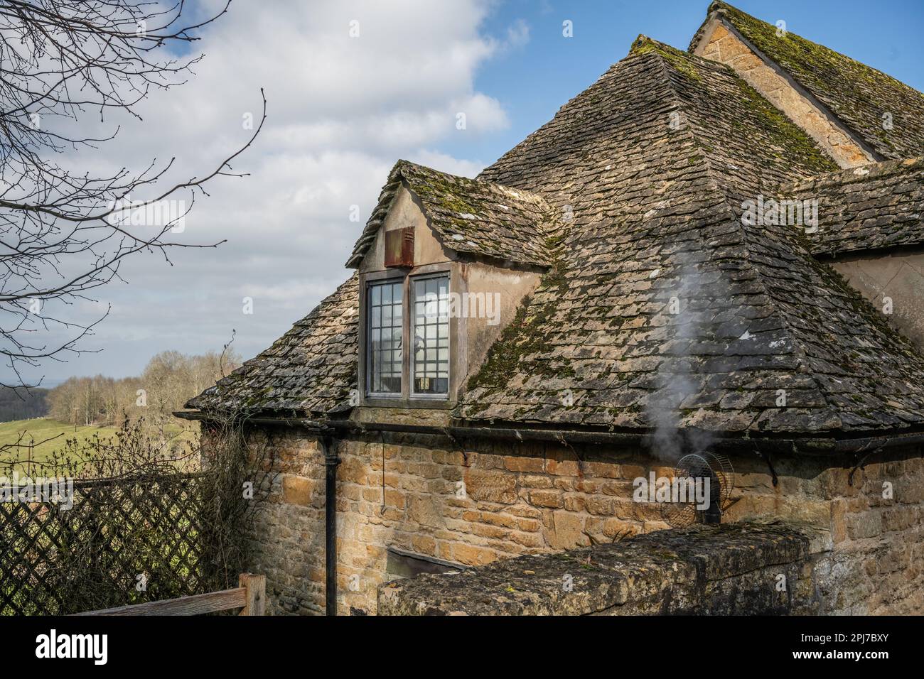 Detail of old traditional windows and roof tiles of stone built cottages in Cotswolds England Stock Photo