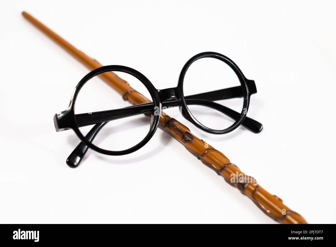 Round black eyeglasses and brown magic wand isolated on white background. Stock Photo