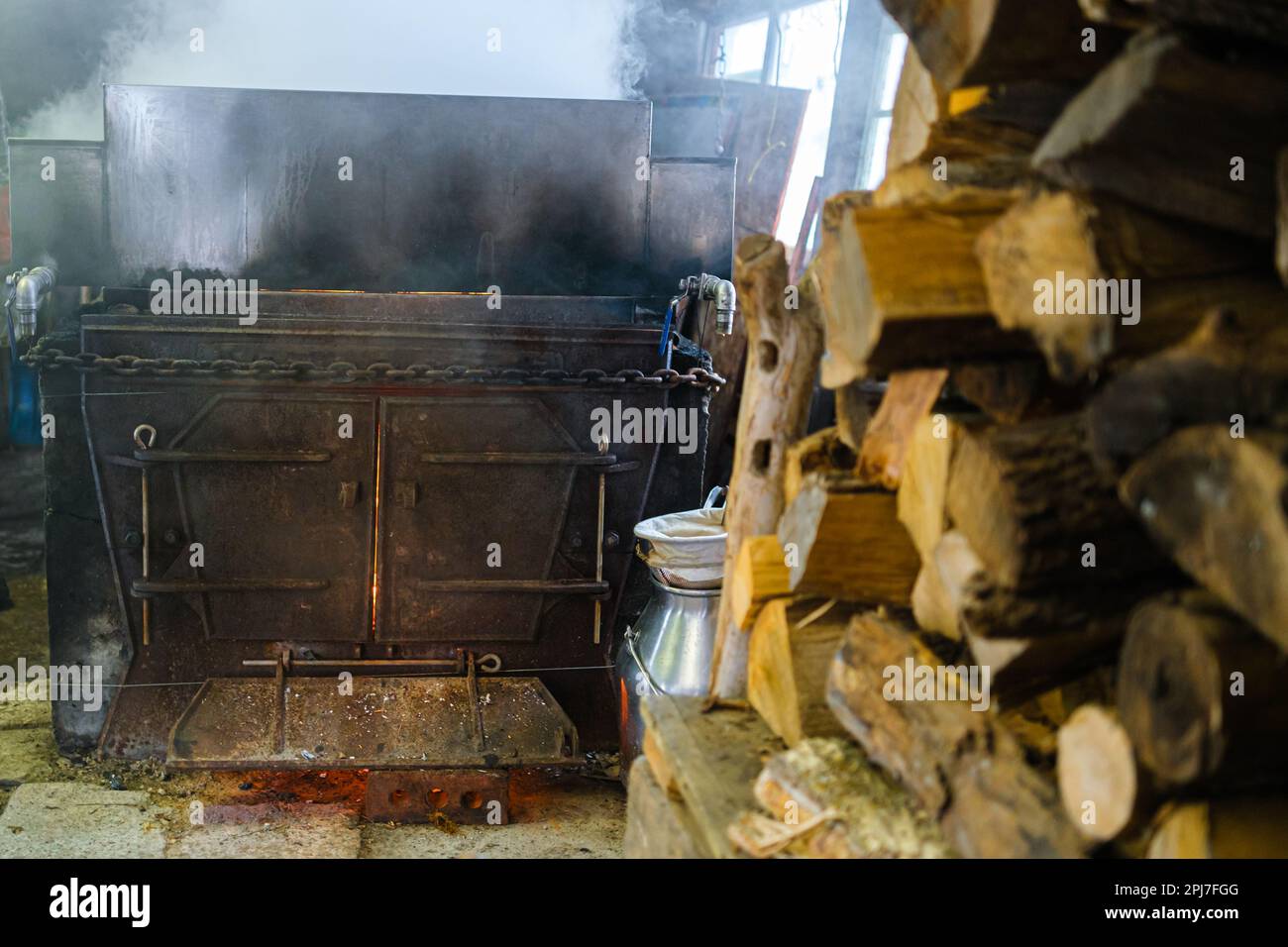 An old evaporator made of dark iron burns wood to evaporate water from