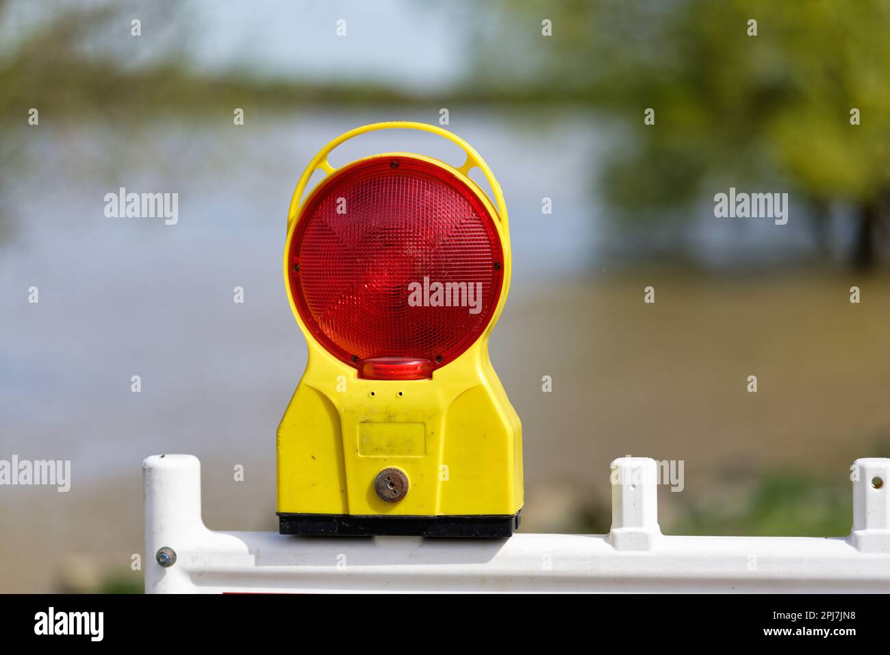 warning light on a barrier grid in front of high water on a river in blurred background Stock Photo