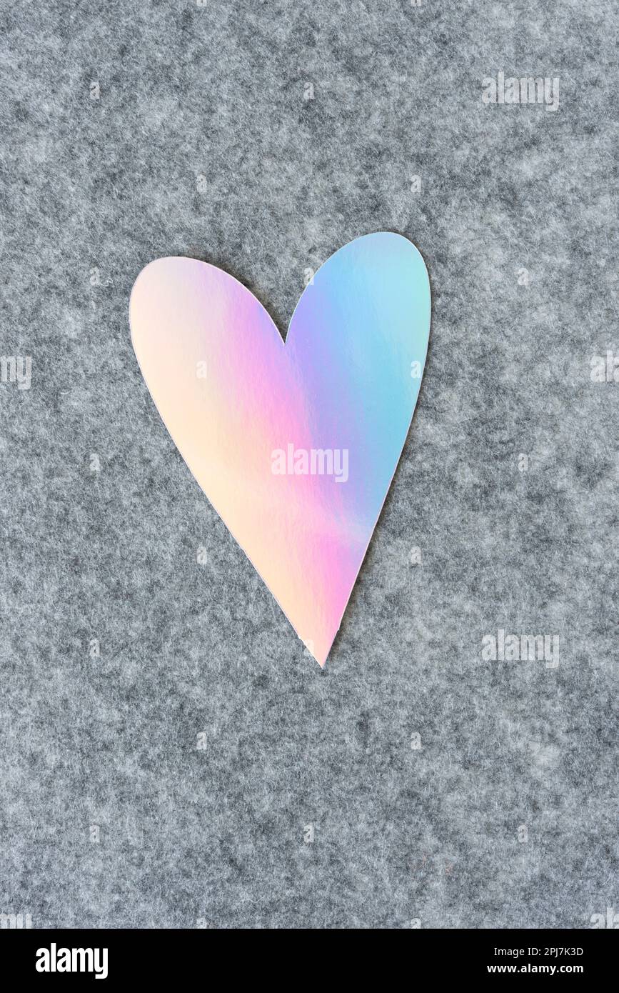 iridescent coloured heart on grey felt material Stock Photo