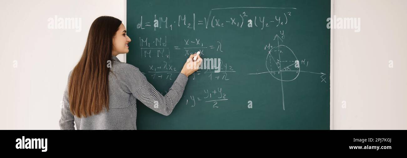 Young teacher writing on chalkboard in classroom. Banner design Stock