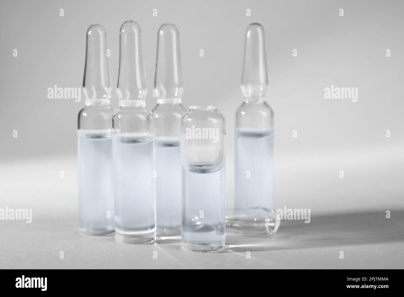 Pharmaceutical ampoules with medication on light grey background Stock