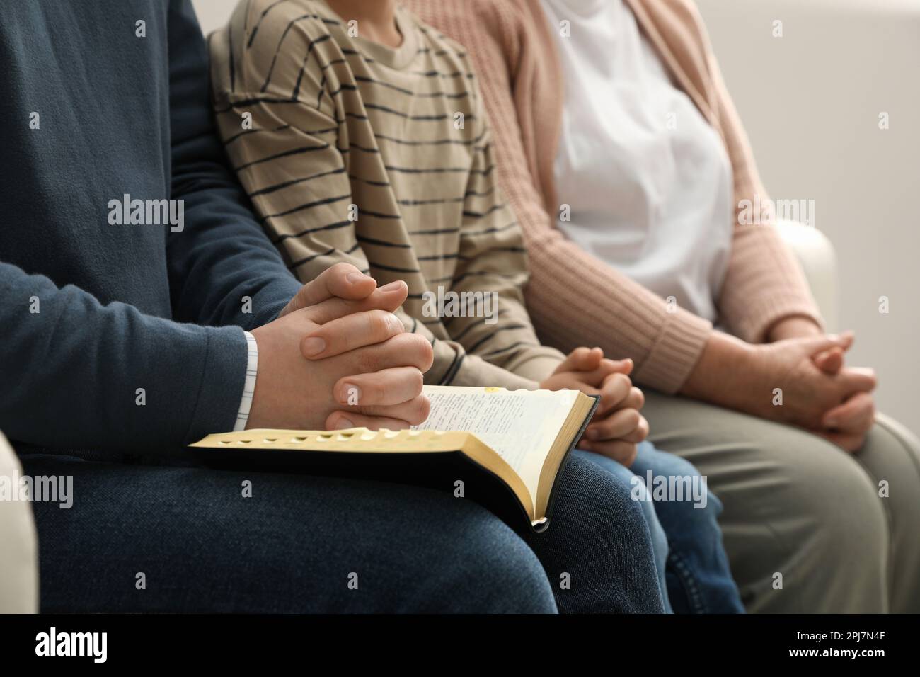 Boy and his godparents praying together indoors, closeup Stock Photo