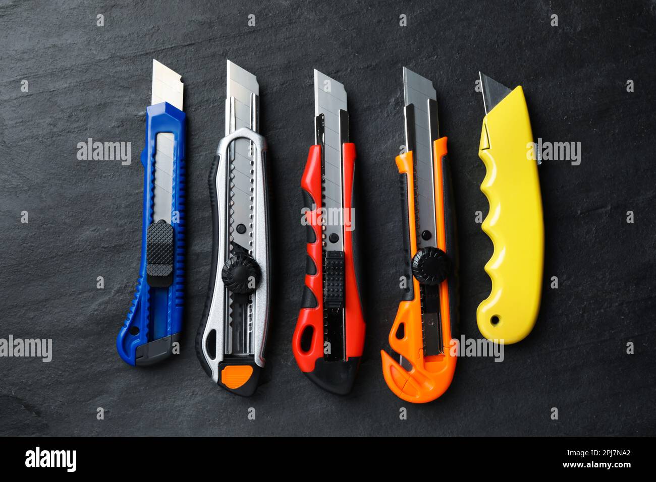Different utility knives on black table, flat lay Stock Photo