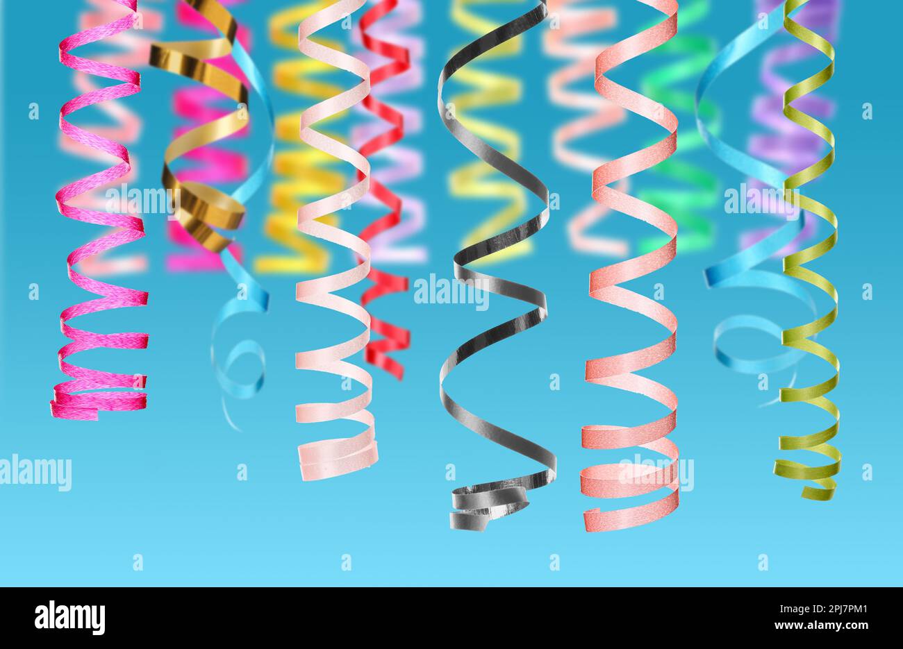 Many serpentine streamers on light blue background. Party decor Stock