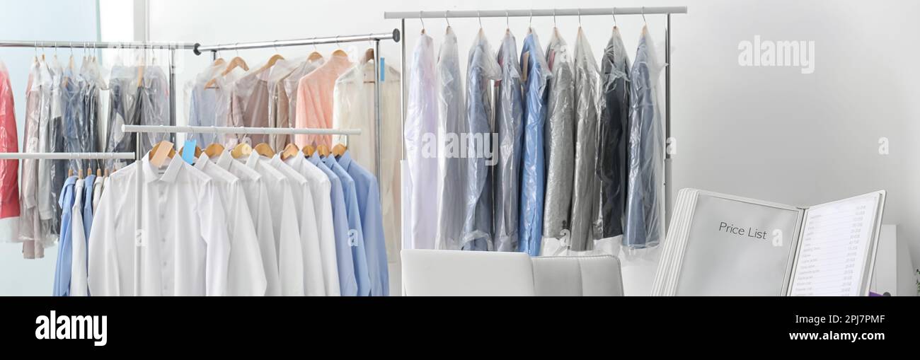 Racks with clean clothes on hangers indoors, banner design. Dry