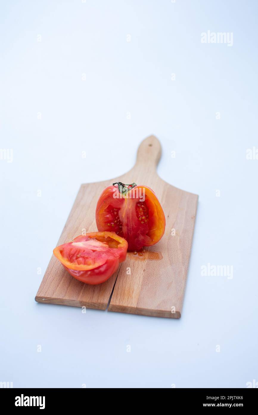 a vertical photo an heirloom tomato cut in half on a small wooden ...