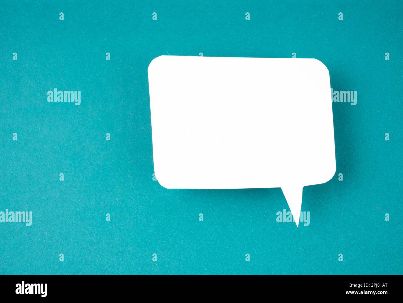 White speech bubble shaped post it note on green background with copy space. Stock Photo