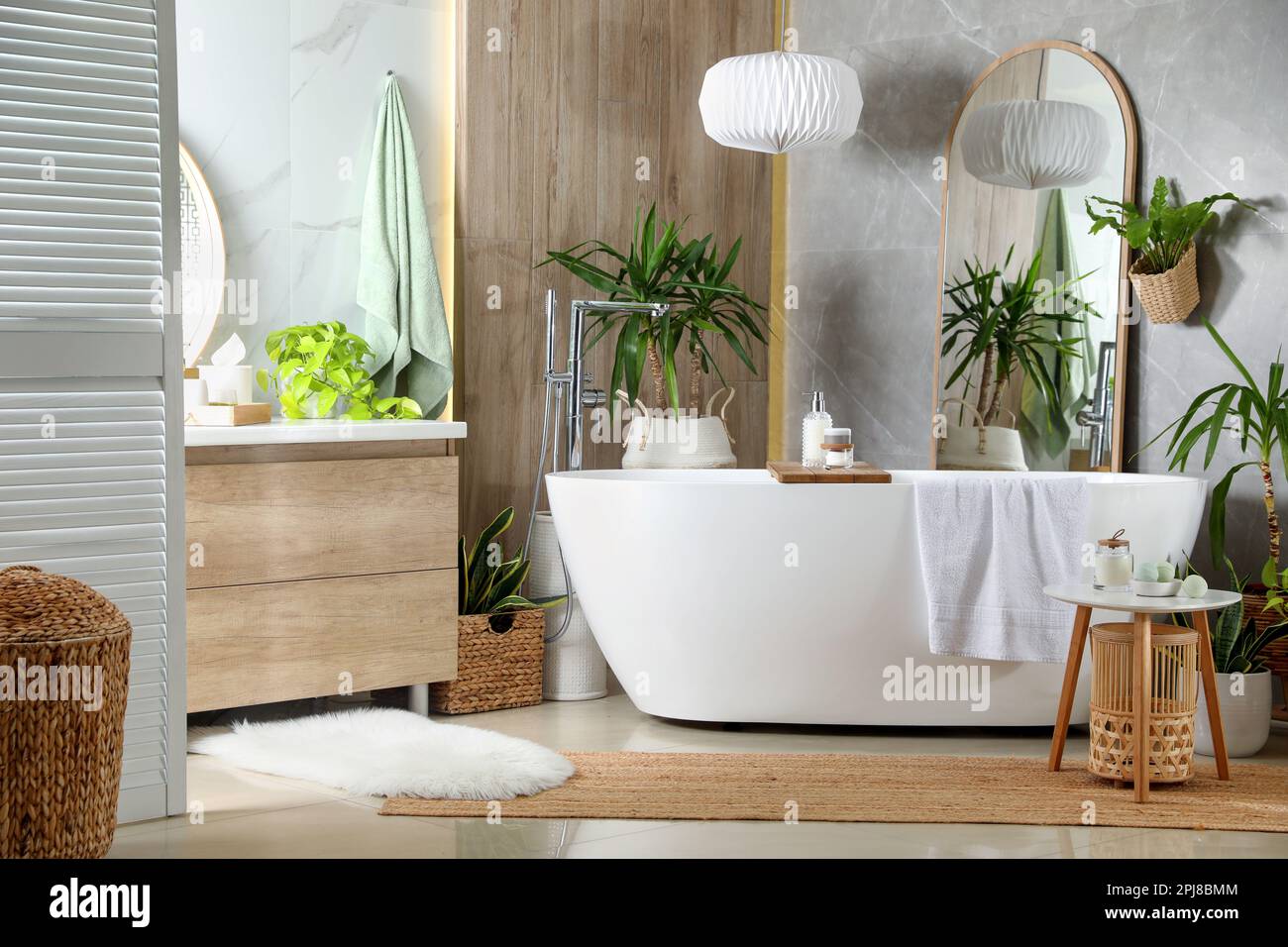 Modern white tub and beautiful green houseplants in bathroom. Interior ...