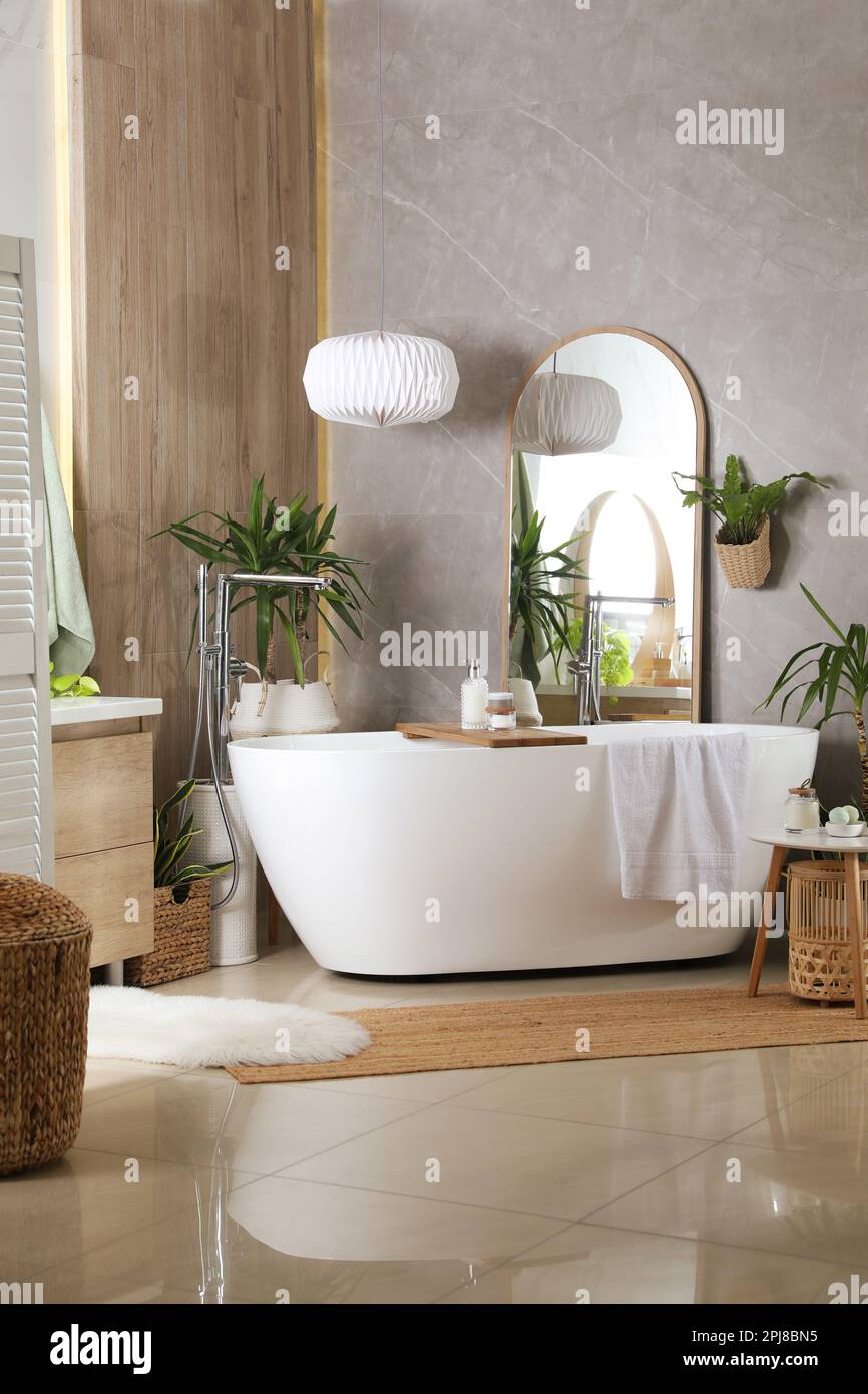 Modern white tub and beautiful green houseplants in bathroom. Interior ...