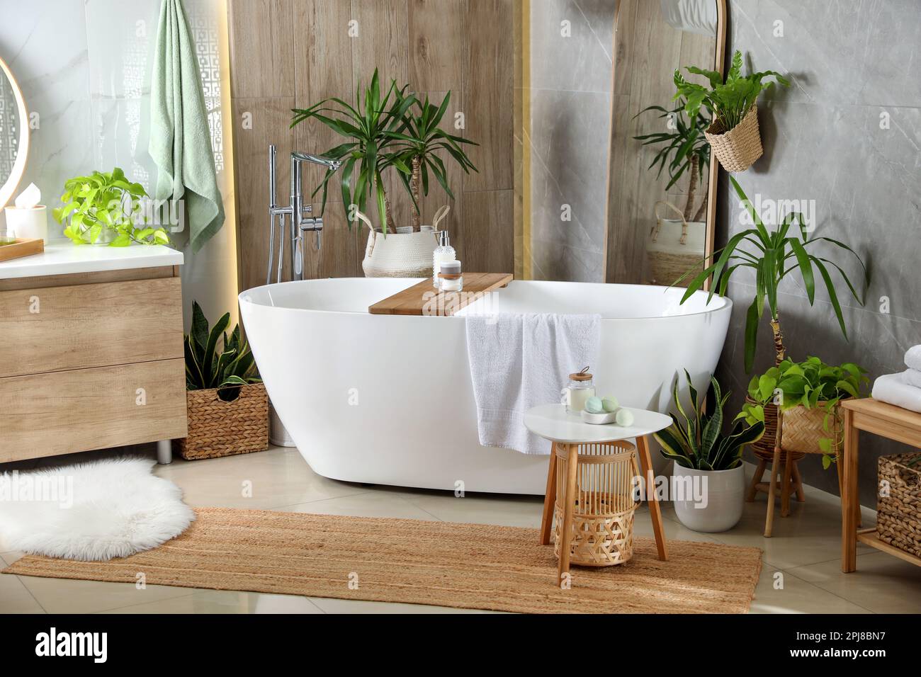 Modern white tub and beautiful green houseplants in bathroom. Interior ...