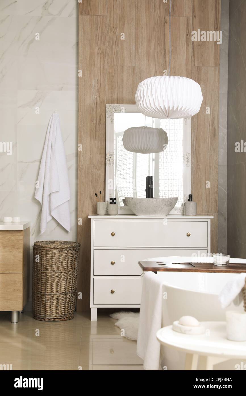 Modern white tub and chest of drawers with sink in bathroom. Interior
