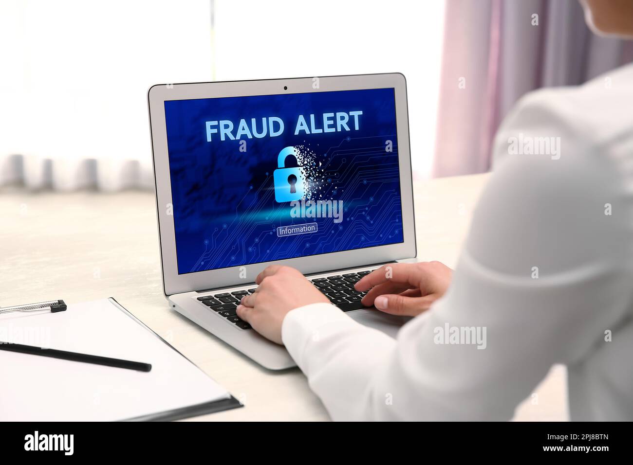 Fraud prevention security system. Woman using laptop at white table, closeup Stock Photo