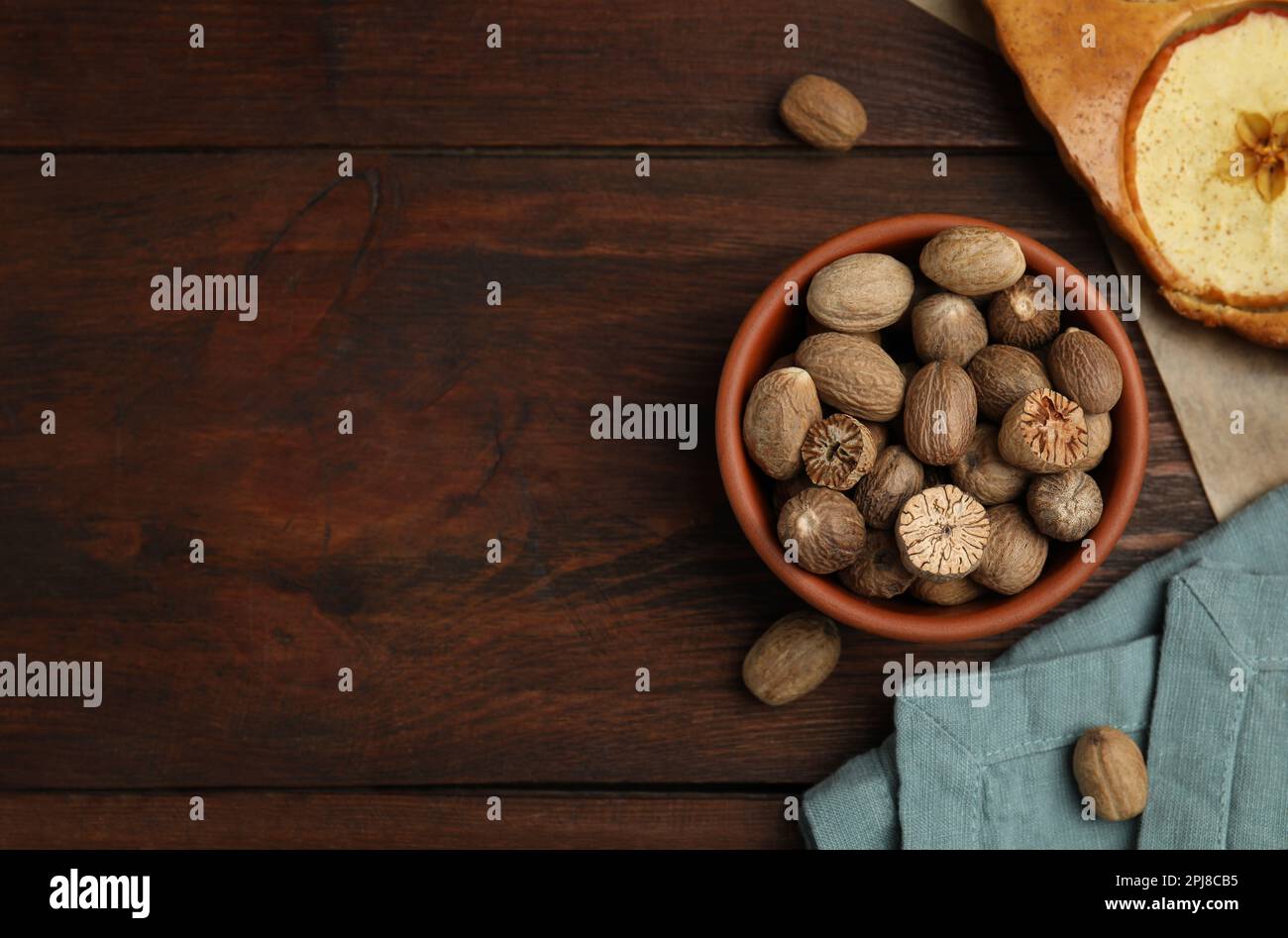 Nutmeg seeds and tasty apple pie on wooden table, flat lay. Space for text Stock Photo
