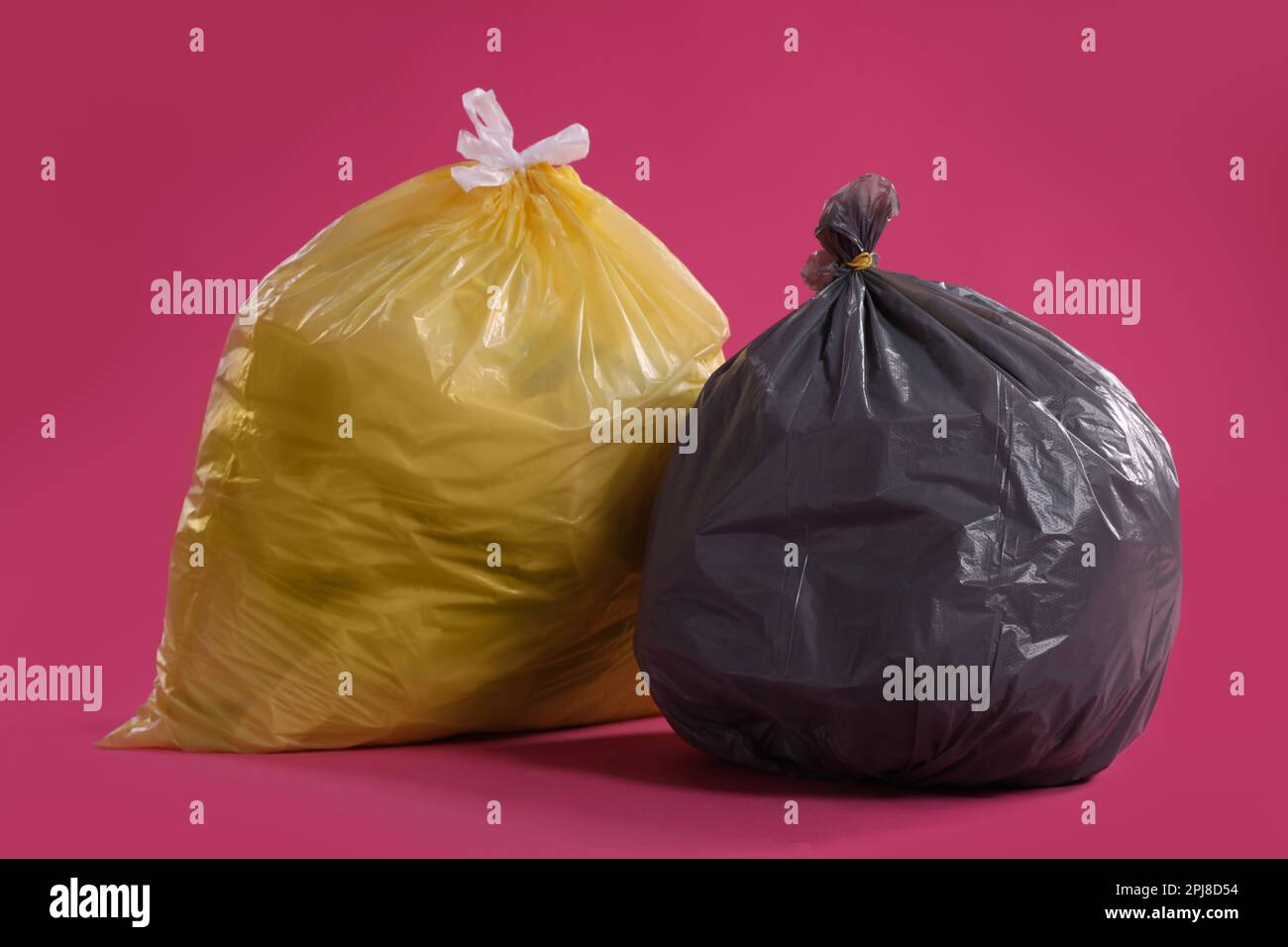 Trash bags full of garbage on pink background Stock Photo - Alamy