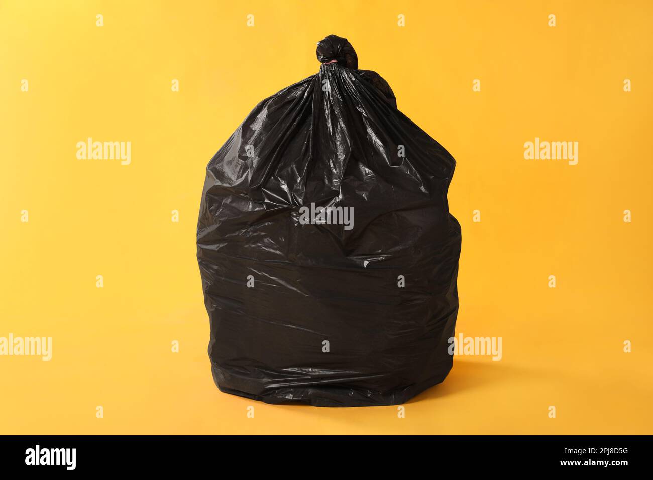 Trash bag full of garbage on yellow background Stock Photo Alamy
