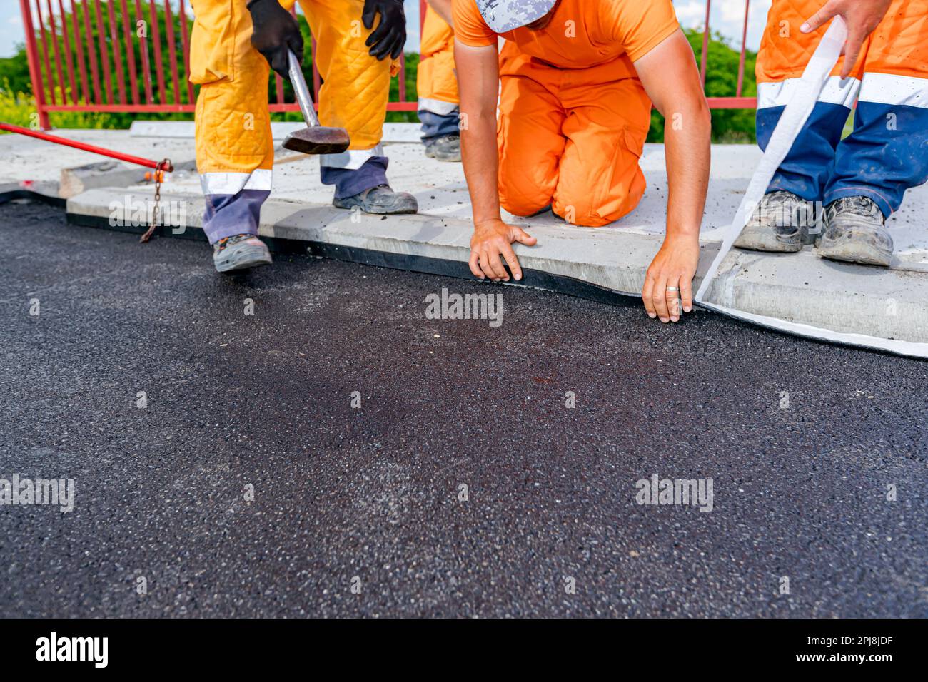 Workers attach a bitumen black tape to protect the roadside of bridge from  water. Waterproofing material designed to resist and prevent water from pas  Stock Photo - Alamy