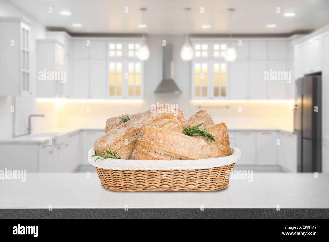 Fresh bread in wicker basket on grey table in kitchen Stock Photo