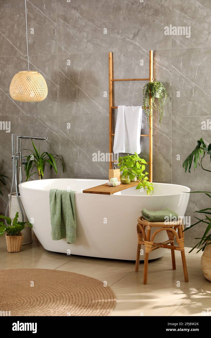 Modern white tub and beautiful green houseplants in bathroom. Interior ...