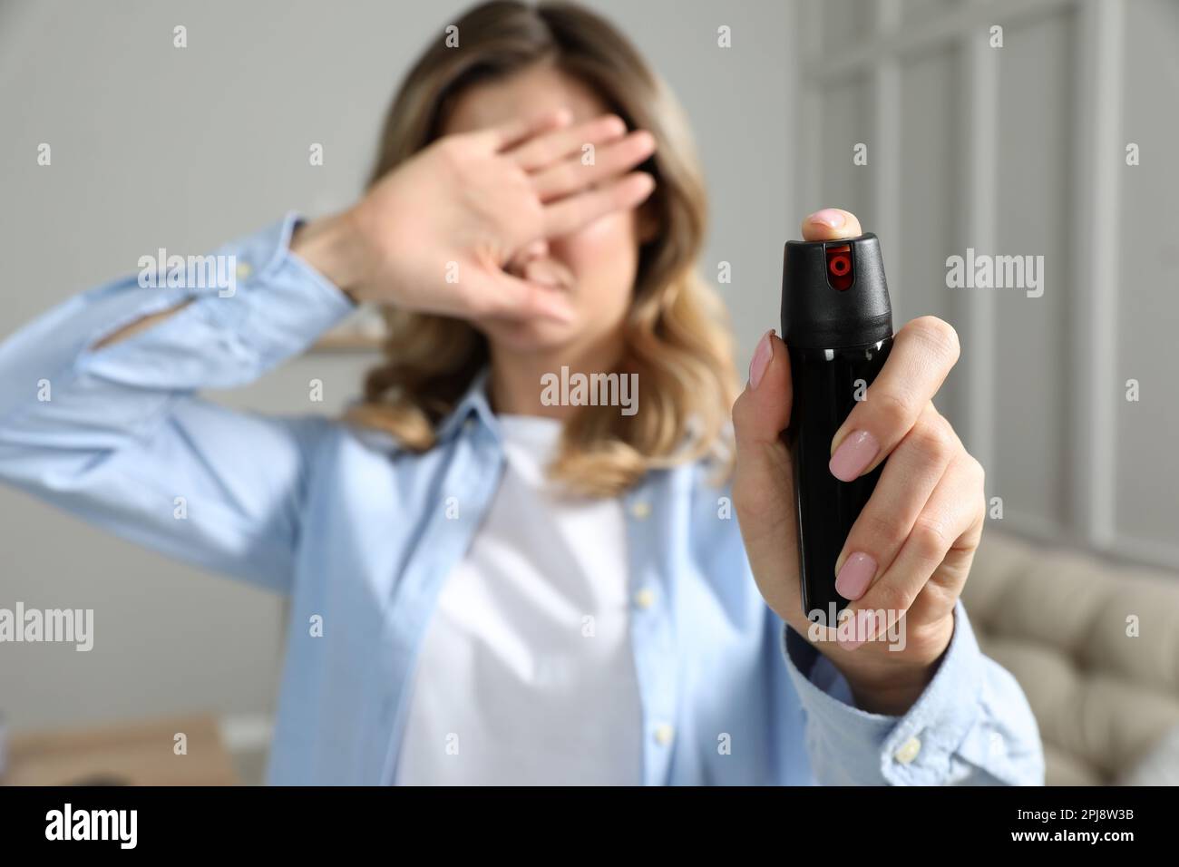 Sprayed Eyes Young woman covering eyes with hand and using pepper spray at home ...