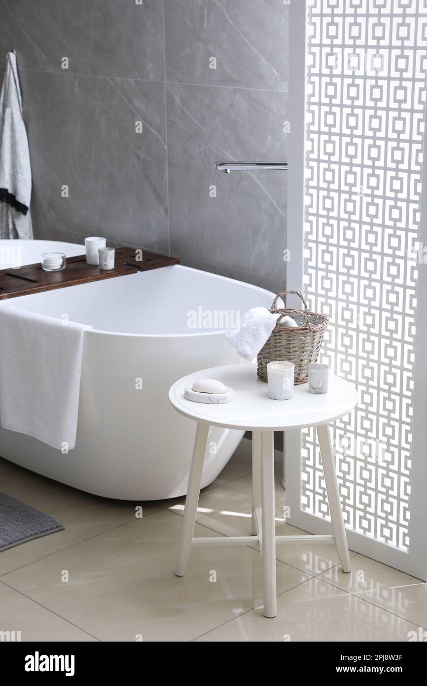 Modern white tub and table with toiletries in bathroom. Interior design ...
