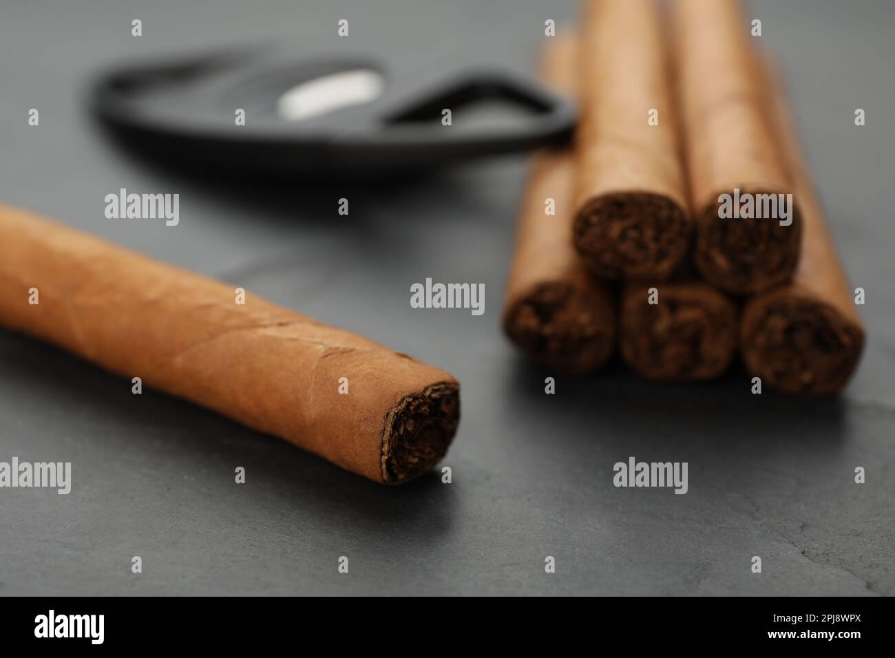Cigars wrapped in tobacco leaves on black table, closeup Stock Photo