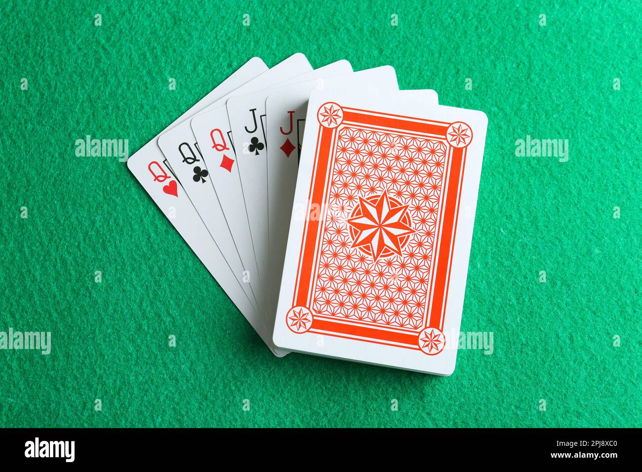 Playing cards with full house combination on green table, top view