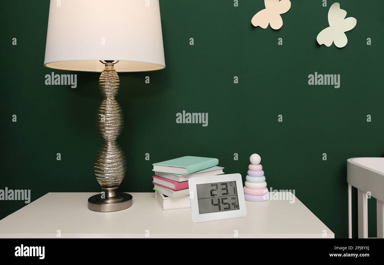 Digital hygrometer with thermometer on white table in children's room. Optimal humidity level for kids Stock Photo