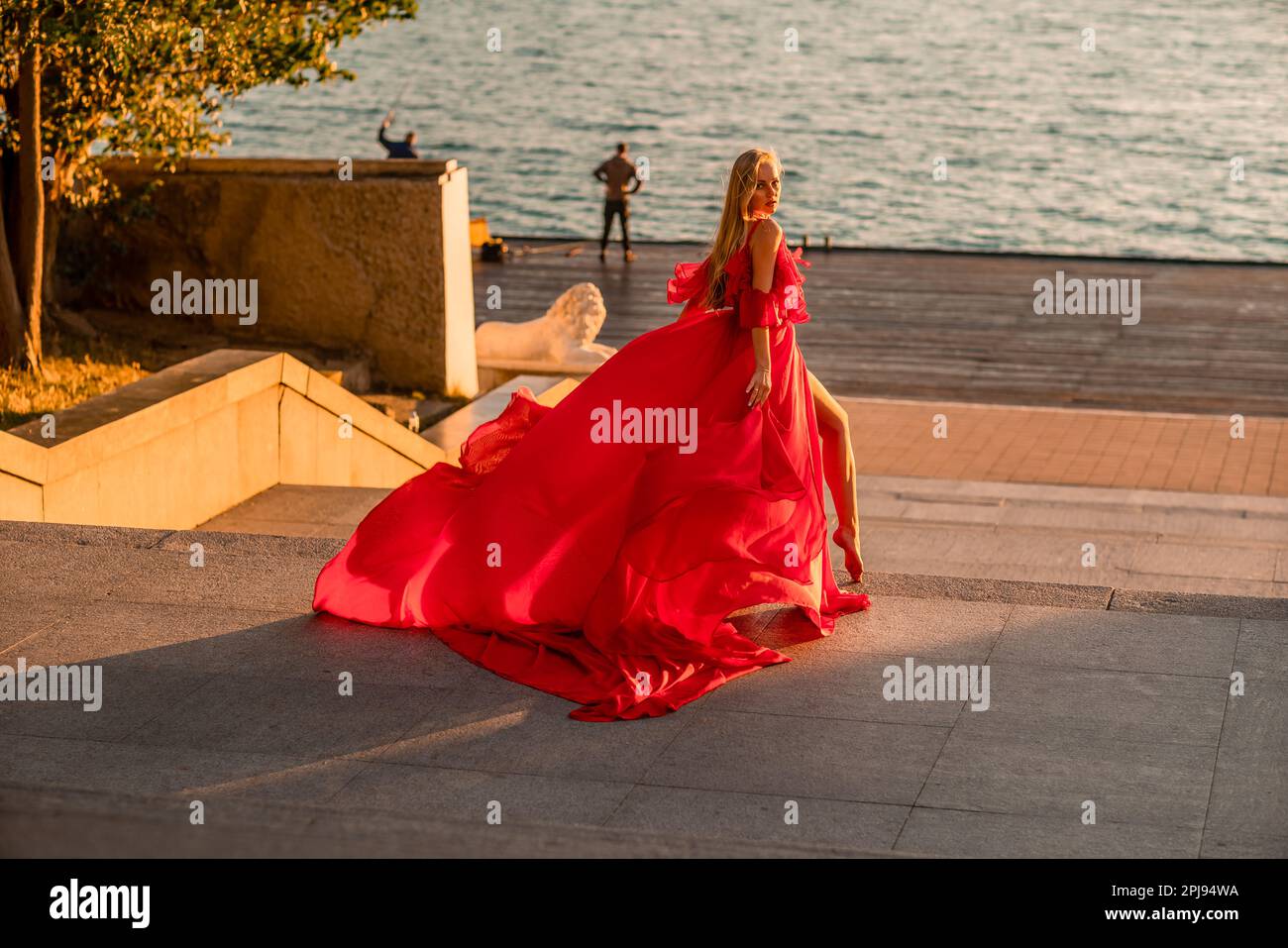 Sunrise red dress. A woman in a long red dress against the backdrop of ...