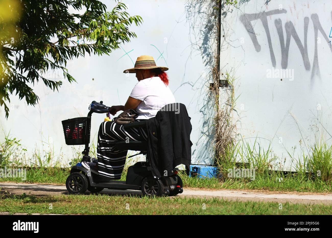 Random street photography of people living their daily life, getting around and doing things. A random women riding away on a mobility scooter. Stock Photo