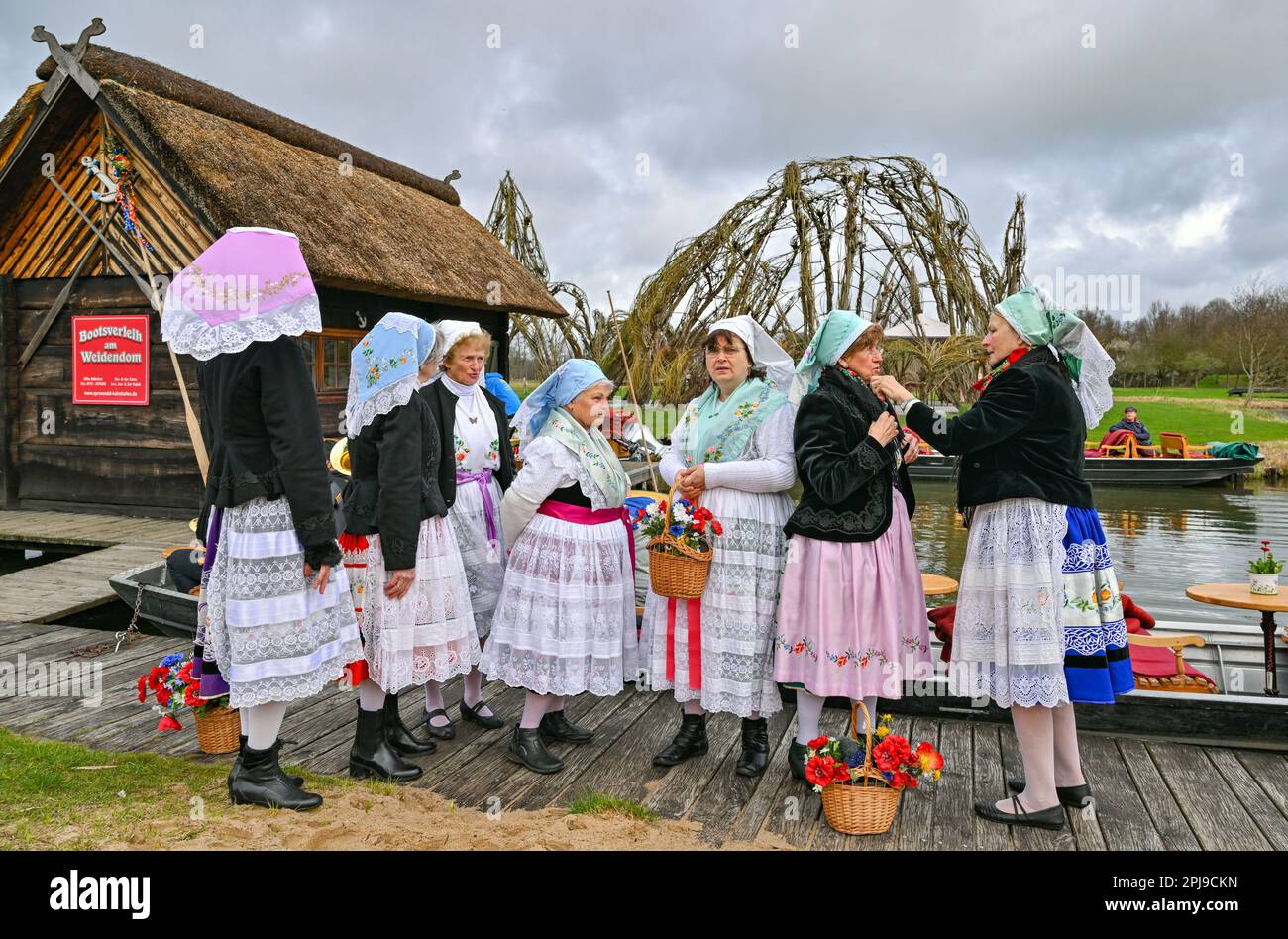 Schlepzig, Germany. 01st Apr, 2023. Women in Sorbian-Wendish festive costumes wait for the season opening at the harbor at the Weidendom in the Spreewald village of Schlepzig. At the opening of the season, the rudel (wooden pole for moving the barge) is ceremoniously handed over to a bargeman. At the same time in several places in the Spreewald the traditional season opening with Rudelübergabe took place. Credit: Patrick Pleul/dpa/Alamy Live News Stock Photo