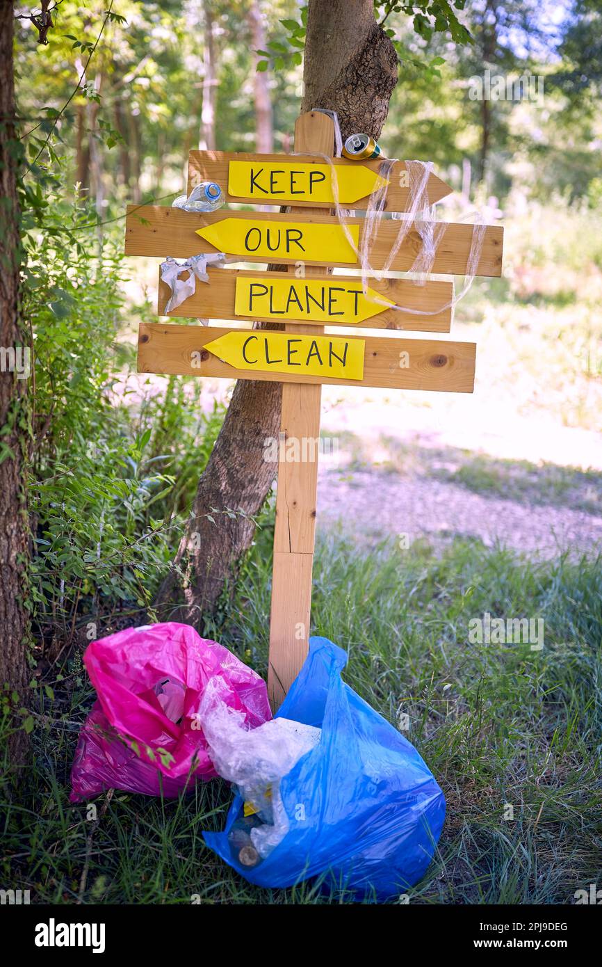 Trash bag next to sign to keep our clean.collecting garbage