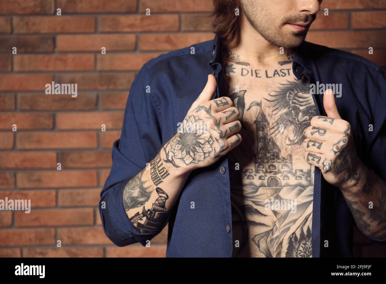 Portrait of a muscular man with tattoo standing on a street by a brick wall  tattoo concept  CanStock
